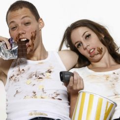 Man and woman eating while watching television on couch