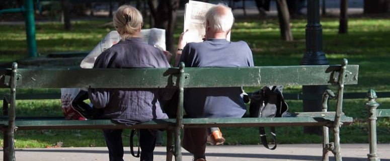 Old People Reading News Papers Sitting On Bench