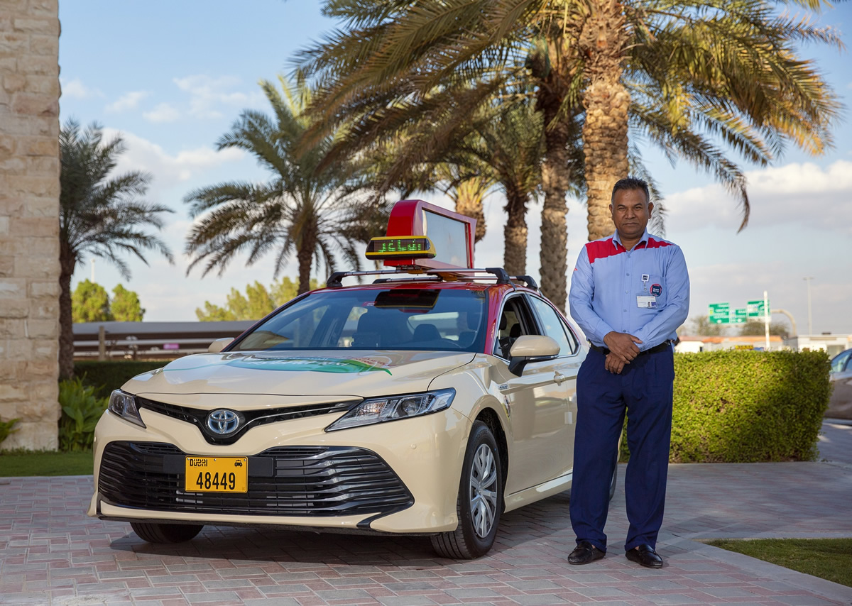 a cab driver stands beside his cab in Dubai